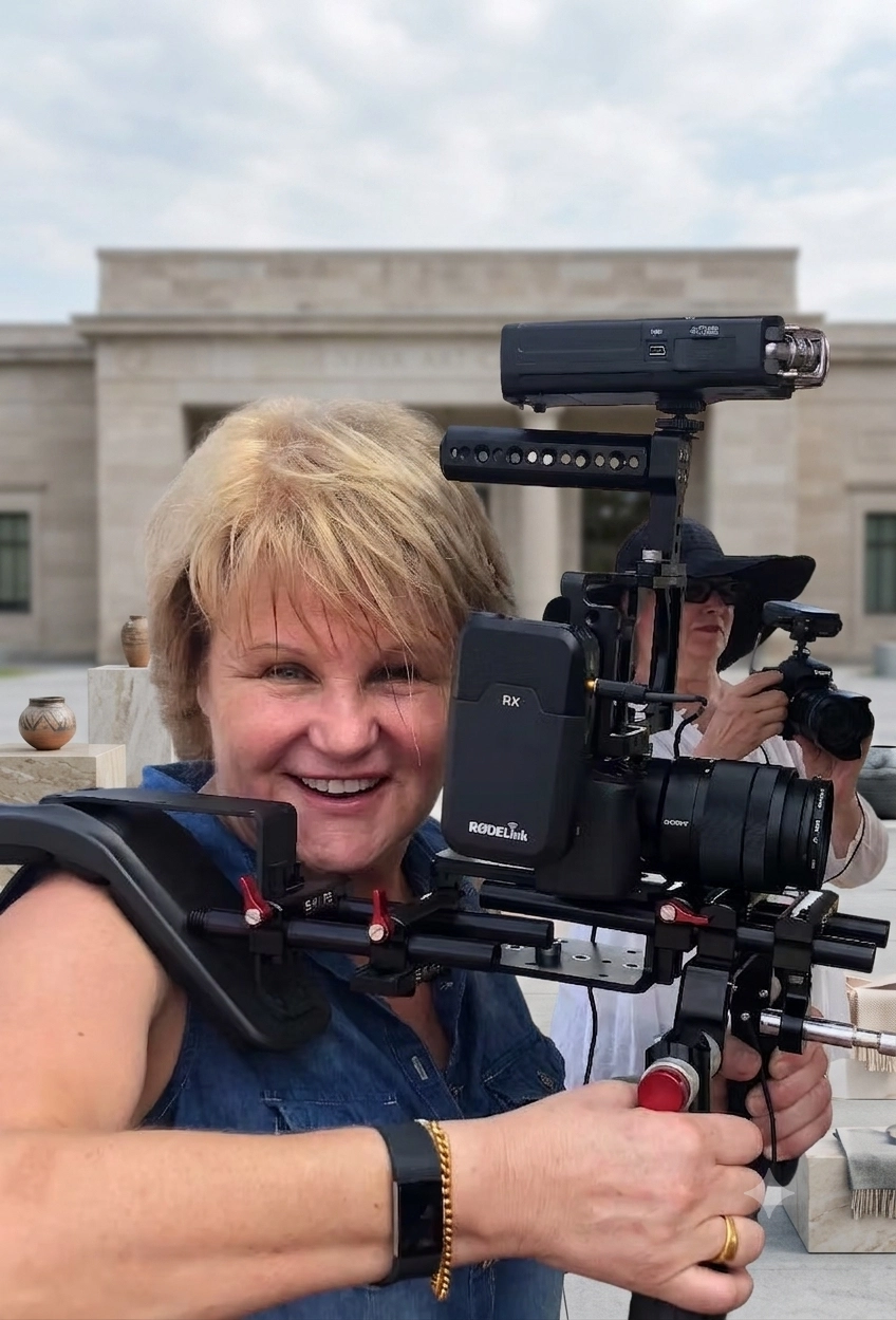 Gillian Arnold Atlas, on-camera acting coach in St. Petersburg, Florida, smiling behind a shoulder-mounted camera rig